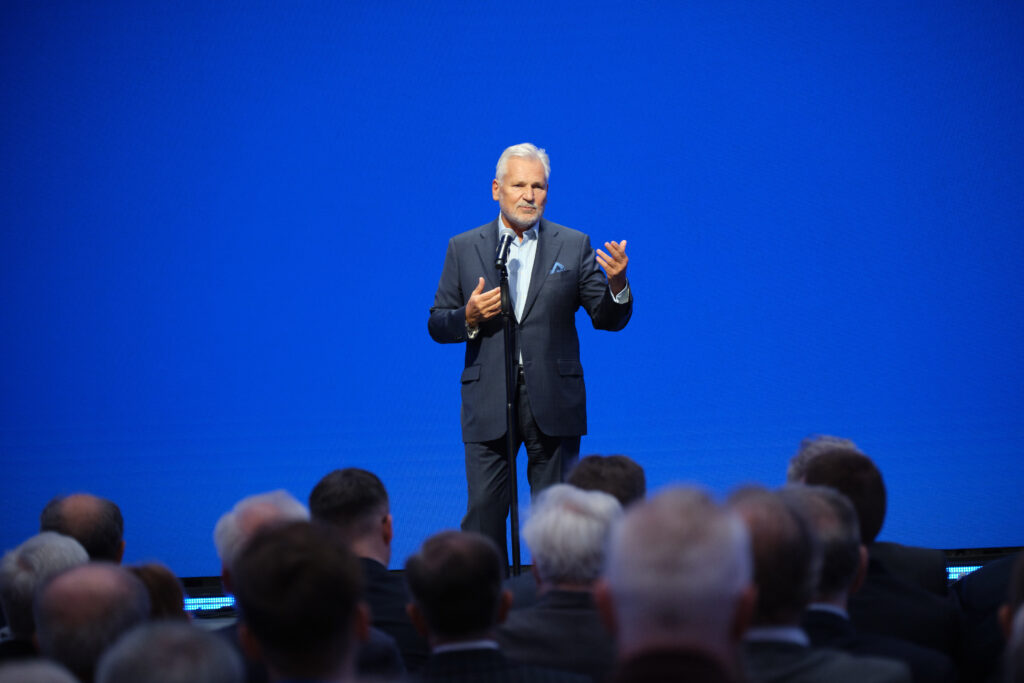 Prezydent Aleksander Kwaśniewski przemawia podczas Gali 75-lecia Ruchu Studenckiego na tle niebieskiego ekranu w Auli Głównej Politechniki Warszawskiej.